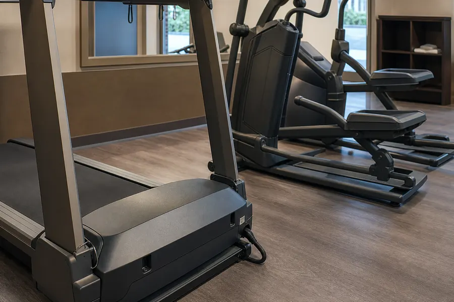 Commercial treadmill and elliptical service access detail in a hotel gym